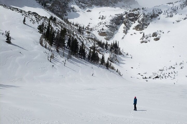 Hiker stands on frozen Emerald Lake in Rocky Mountain National Park.